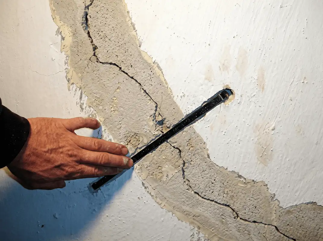 A wall with a large crack is being inspected by a professional in Hollywood, FL